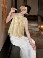 Sitting model in a gold Cheongsam top and white wide-leg trousers, holding a decorative fan, crafted from 100% polyester.