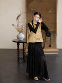 Full-body styling of a gold Zhangduan silk Chinese vest paired with a long black floral skirt.