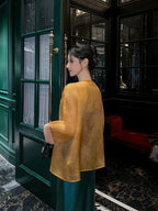 Back view of a lightweight golden amber pure silk cardigan featuring a fluid drape and sheer finish.