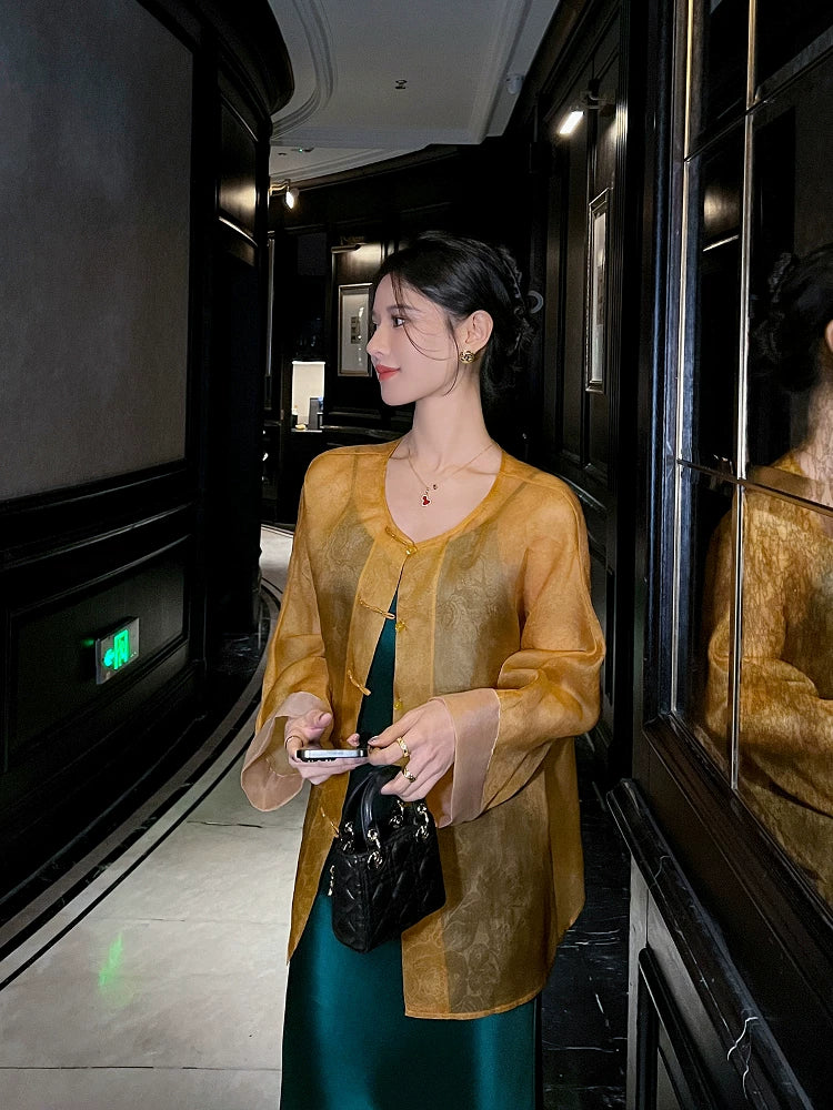 Side profile of a woman wearing a lightweight golden amber silk cardigan with a relaxed silhouette.