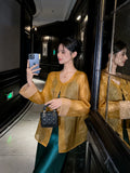 Golden amber pure silk cardigan styled for an elegant evening look with a flowing emerald dress.