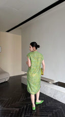 Back view of a sage green Cheongsam dress with a sleeveless design and textured fabric, paired with green heels and a matching bag.