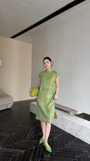 Front view of a sage green Qipao dress with frog buttons and a flowy silhouette, styled with green heels and a matching bag.