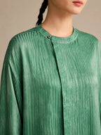 Close-up of the round neckline and single-button closure, highlighting the detailed water-rippled crinkled texture of the breathable 100% mulberry silk.