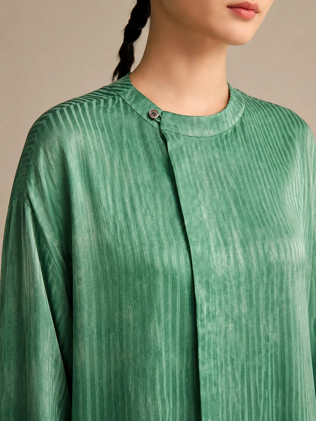 Close-up of the round neckline and single-button closure, highlighting the detailed water-rippled crinkled texture of the breathable 100% mulberry silk.