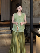 Front view of a green sleeveless embroidered vest with buttoned front, styled with a pleated skirt and white bag, crafted from 100% polyester.
