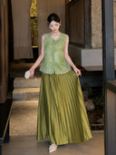 Side view of a green sleeveless vest with delicate embroidery and scalloped lace hem, paired with a pleated skirt, crafted from 100% polyester.