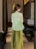 Back view of a green embroidered sleeveless vest with scalloped lace hem, paired with a pleated skirt, highlighting the elegant embroidery details.