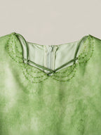 Close-up detail of green mulberry silk dress featuring delicate bead embroidery on the neckline and soft watercolor dyeing texture