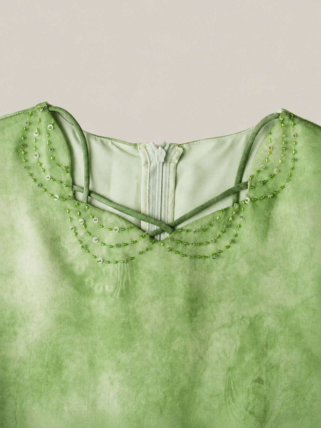 Close-up detail of green mulberry silk dress featuring delicate bead embroidery on the neckline and soft watercolor dyeing texture
