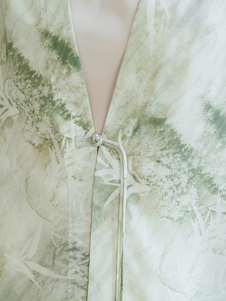 Close-up of the tie closure and watercolor print on a 100% mulberry silk open-front shirt, highlighting the intricate bamboo leaf motifs and the knot detail.