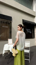 Back view of green palazzo pants with an elasticated waist, paired with a white sheer blouse, showcasing the full length and relaxed silhouette.