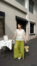Full body shot of olive green wide-leg trousers, styled with a white blouse and white heels, perfect for a chic summer look.
