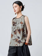 Side profile of a women's grey silk tank top with brown piping and an abstract floral pattern, styled with black pants and a brown bag.