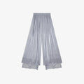 Flat lay of grey pleated wide-leg pants with an elastic waistband, side tie, and layered lace hem, crafted from 100% polyester.