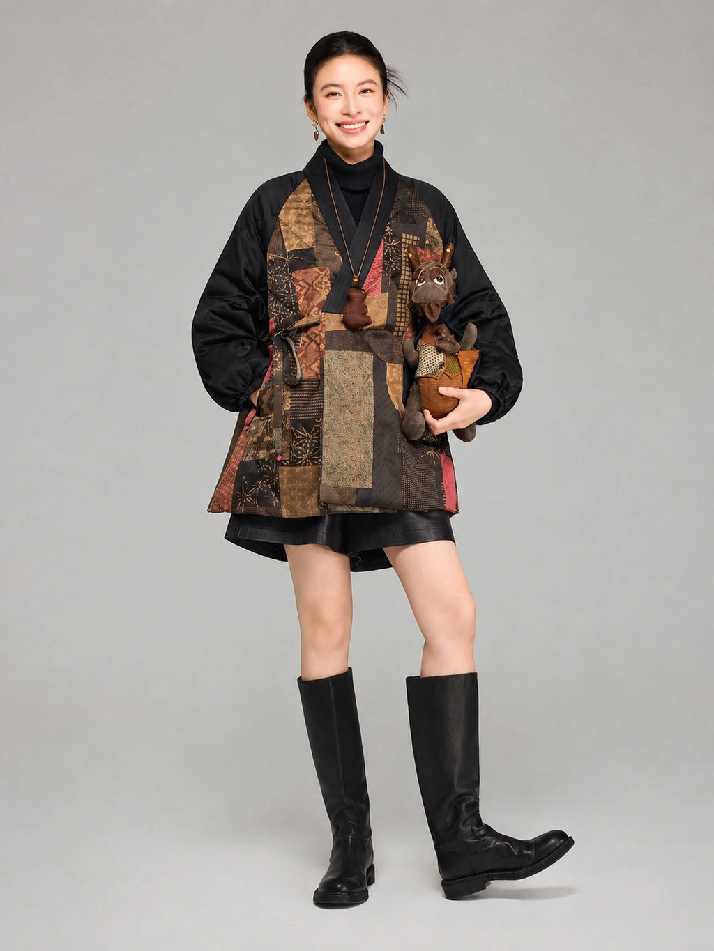 Front view of a women’s mid-length Gambiered Silk down coat featuring bronze, red and teal patchwork-style patterns.