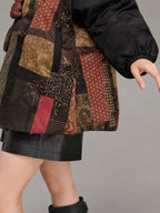 Close-up of the patterned silk hem, concealed pocket opening and gathered black sleeve cuff.