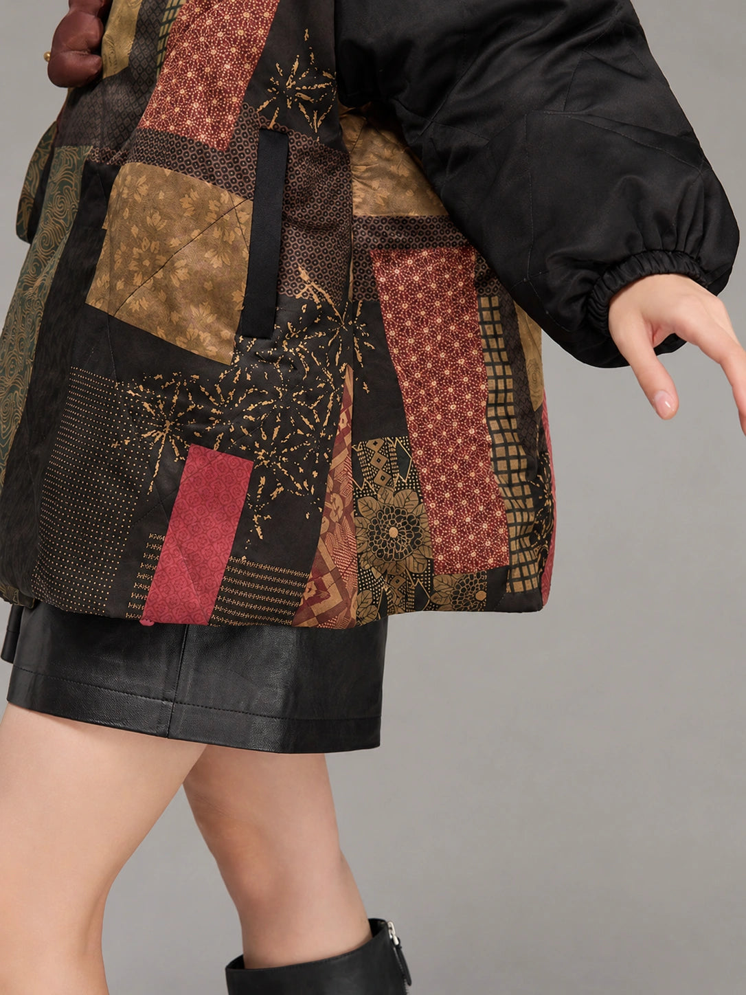 Close-up of the patterned silk hem, concealed pocket opening and gathered black sleeve cuff.