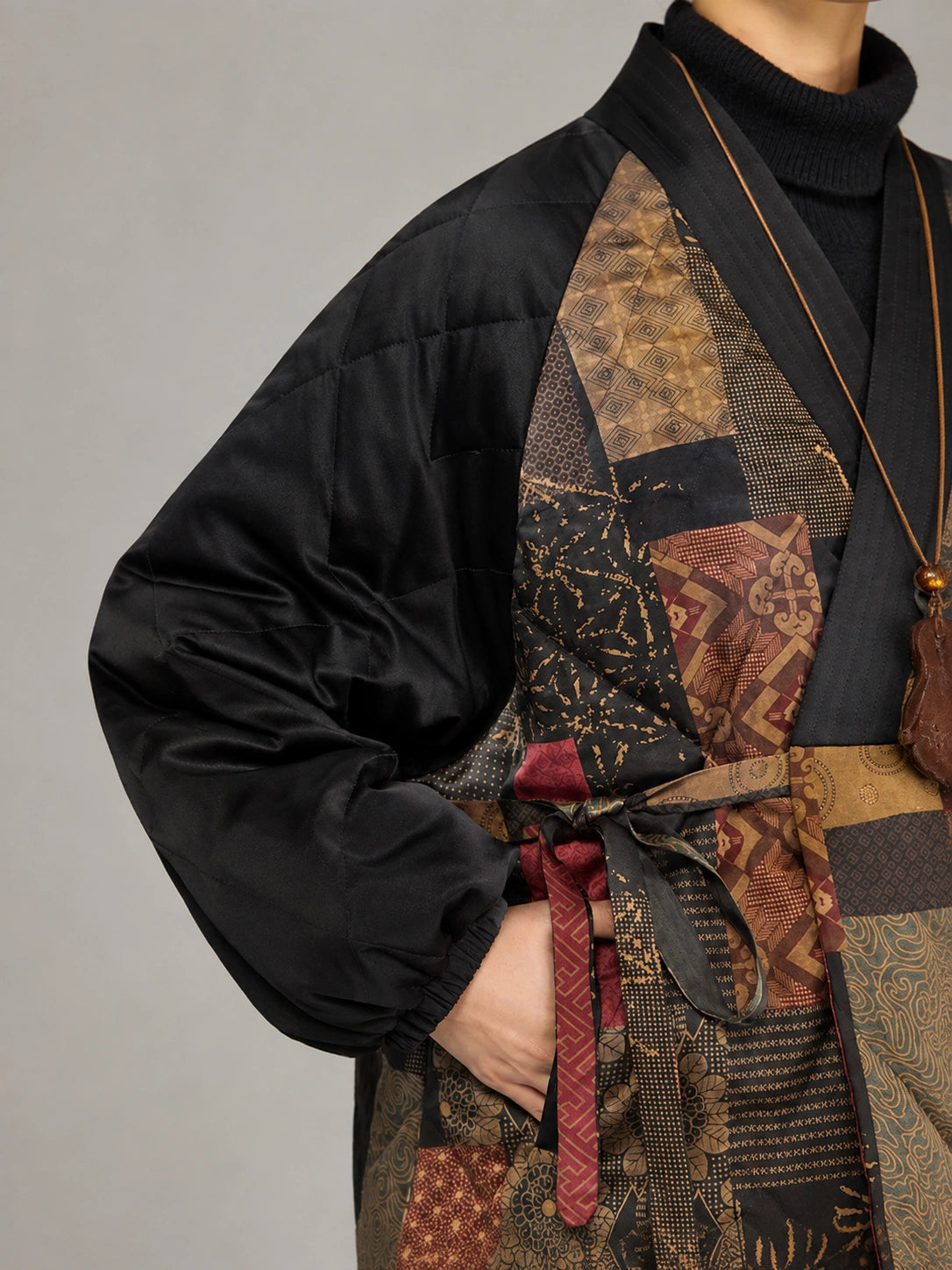 Detail view of the black quilted sleeve, patterned silk panels and adjustable waist tie.