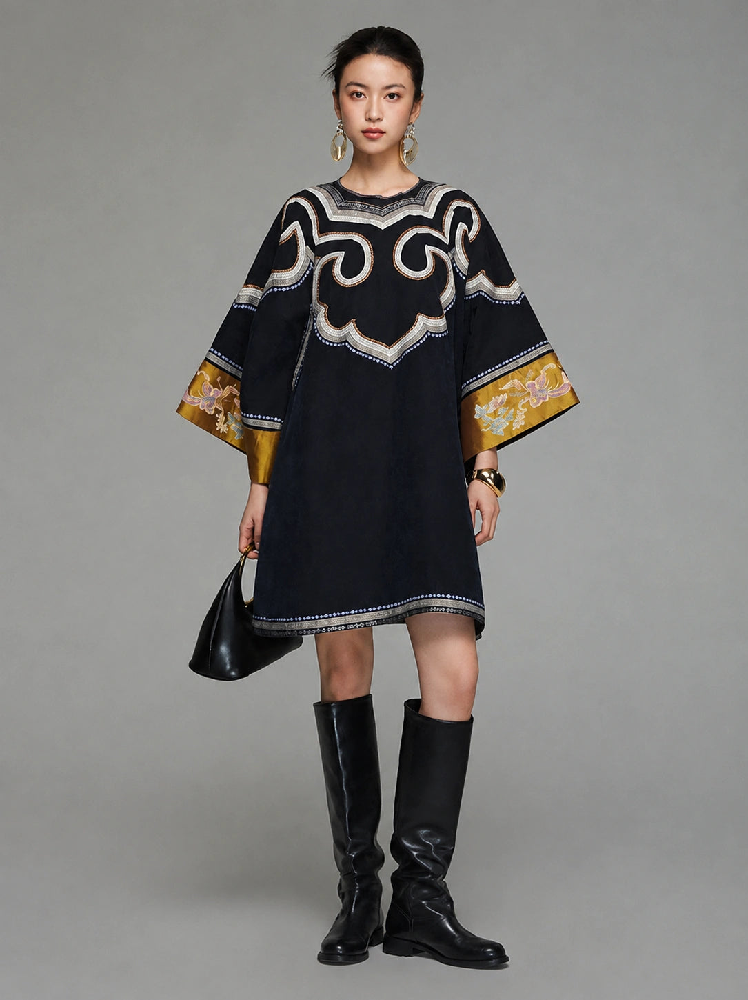 Model wearing a heritage-inspired navy silk tunic dress with round neckline and embroidered wide sleeves
