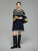 Front view of a woman wearing the midnight navy Xiangyunsha silk tunic dress with embroidered scroll motifs and golden cuffs