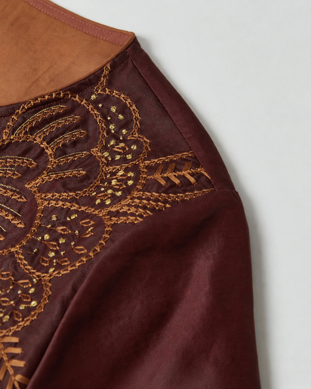 Detailed view of the amber and gold botanical embroidery on the wine-red mulberry silk dress