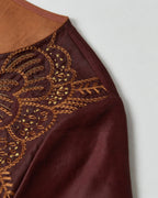 Detailed view of the amber and gold botanical embroidery on the wine-red mulberry silk dress