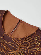 Close-up of the round neckline, back keyhole and amber botanical embroidery on red Hongyunsha silk