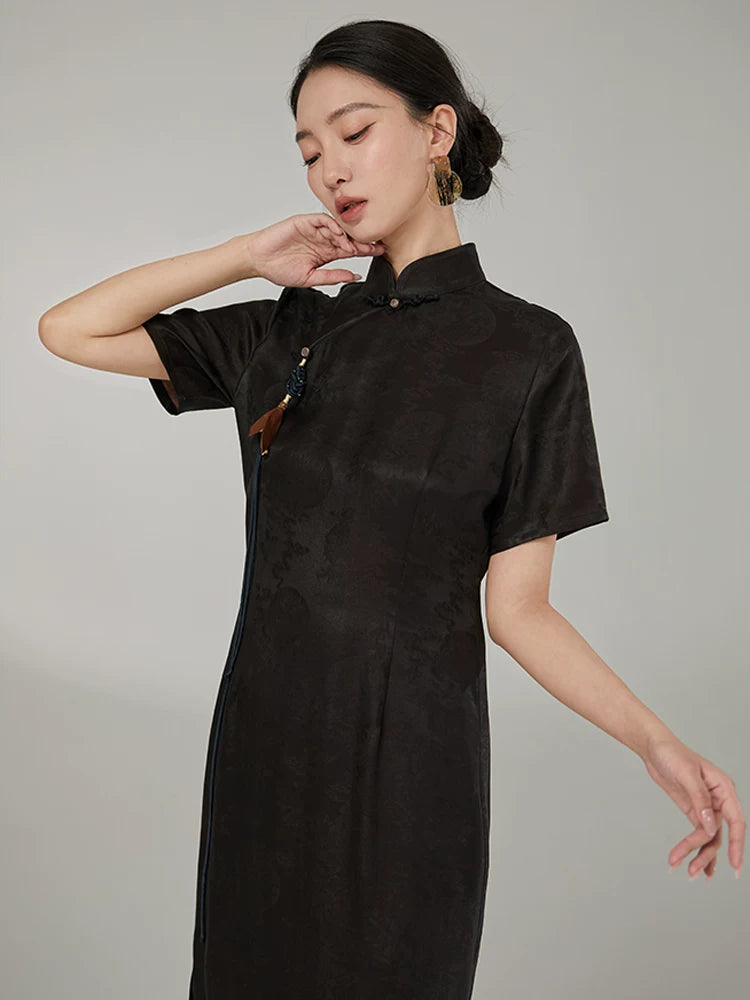Close-up of the mandarin collar, handcrafted tassel, and jacquard silk fabric on an elegant black cheongsam dress.