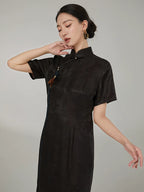 Close-up of the mandarin collar, handcrafted tassel, and jacquard silk fabric on an elegant black cheongsam dress.