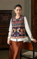 Model wearing the Gilded Ochre embroidered vest beside a wooden cabinet