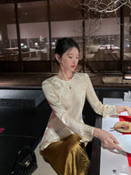 Woman wearing an ivory acetate jacquard long sleeve blouse with a subtle floral woven pattern at an elegant restaurant.