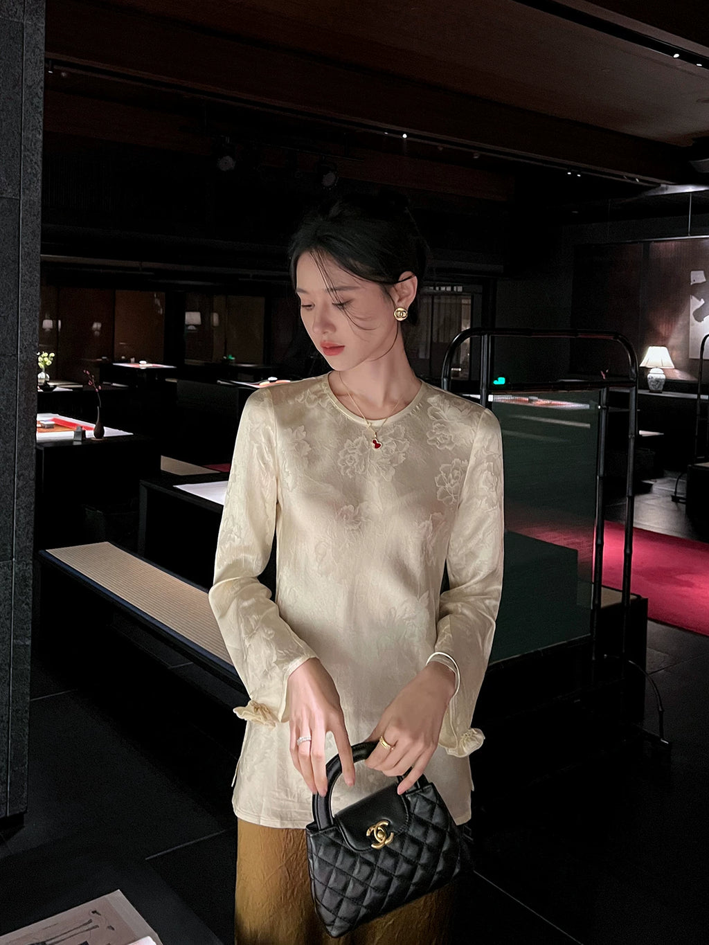Front view of a woman wearing an ivory acetate jacquard blouse styled with a satin bronze skirt.