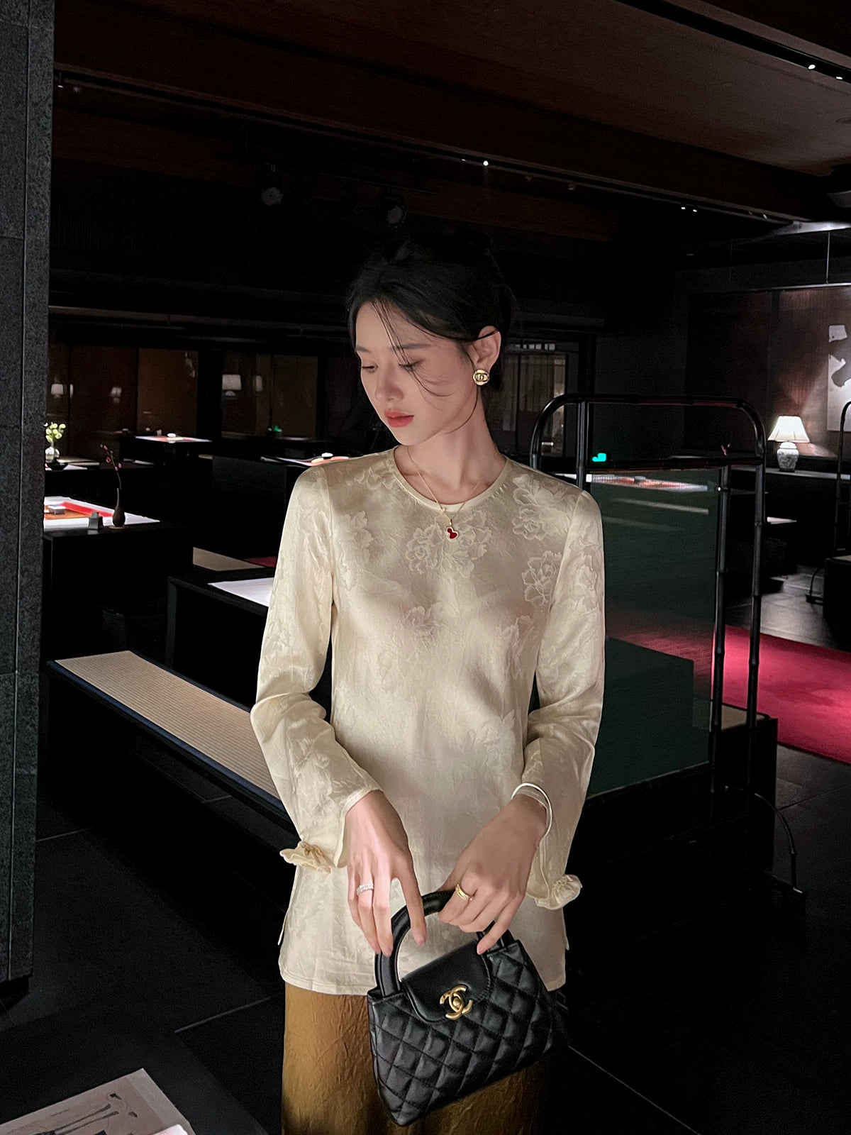 Front view of a woman wearing an ivory acetate jacquard blouse styled with a satin bronze skirt.