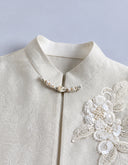 Close-up of the stand collar and beaded neckline detail beside dimensional flowers made from ivory sequins and beads.