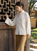 Front view of an ivory floral jacquard jacket featuring a stand collar, rounded buttons and dimensional bead and sequin flowers.