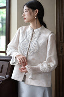 Side portrait by a window highlighting the vest’s blue embroidery and stand collar.