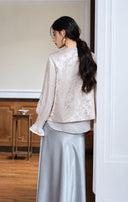 Back view of the ivory floral-jacquard vest styled with a long-sleeve top and skirt.