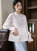 Three-quarter view of the ivory embroidered vest layered over a sheer-sleeve top.