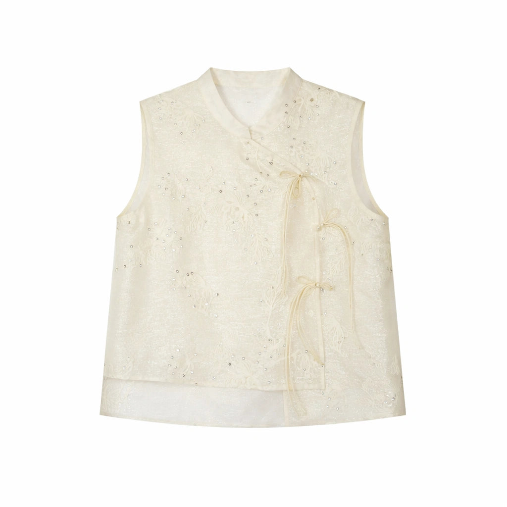 Flat lay of an ivory sleeveless embroidered vest with a mandarin collar, floral embroidery, and side tie details.