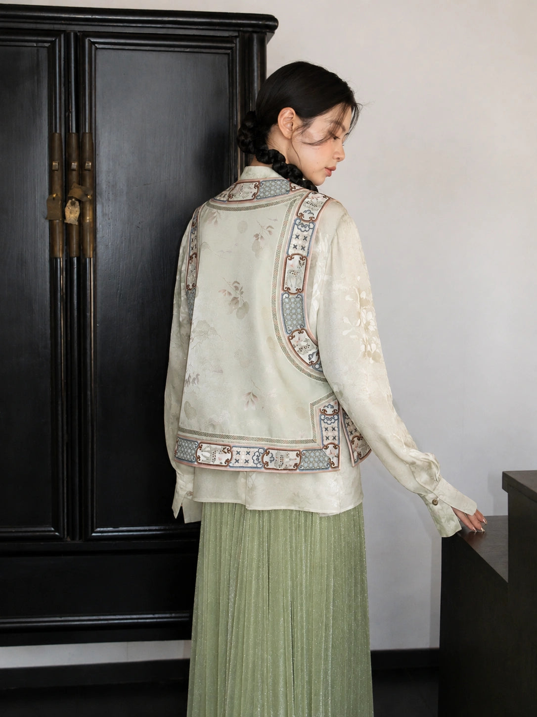 Back view of an ivory floral silk Chinese vest with decorative embroidered panels and a stand collar.