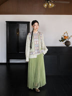 Full-body styling of an ivory 100% mulberry silk Chinese vest paired with a sage green pleated skirt.