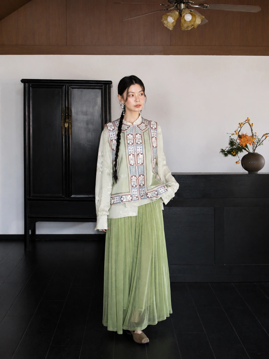 Full-body styling of an ivory 100% mulberry silk Chinese vest paired with a sage green pleated skirt.