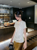Close-up of an ivory silk blend jacquard blouse with a relaxed fit and subtle woven texture.