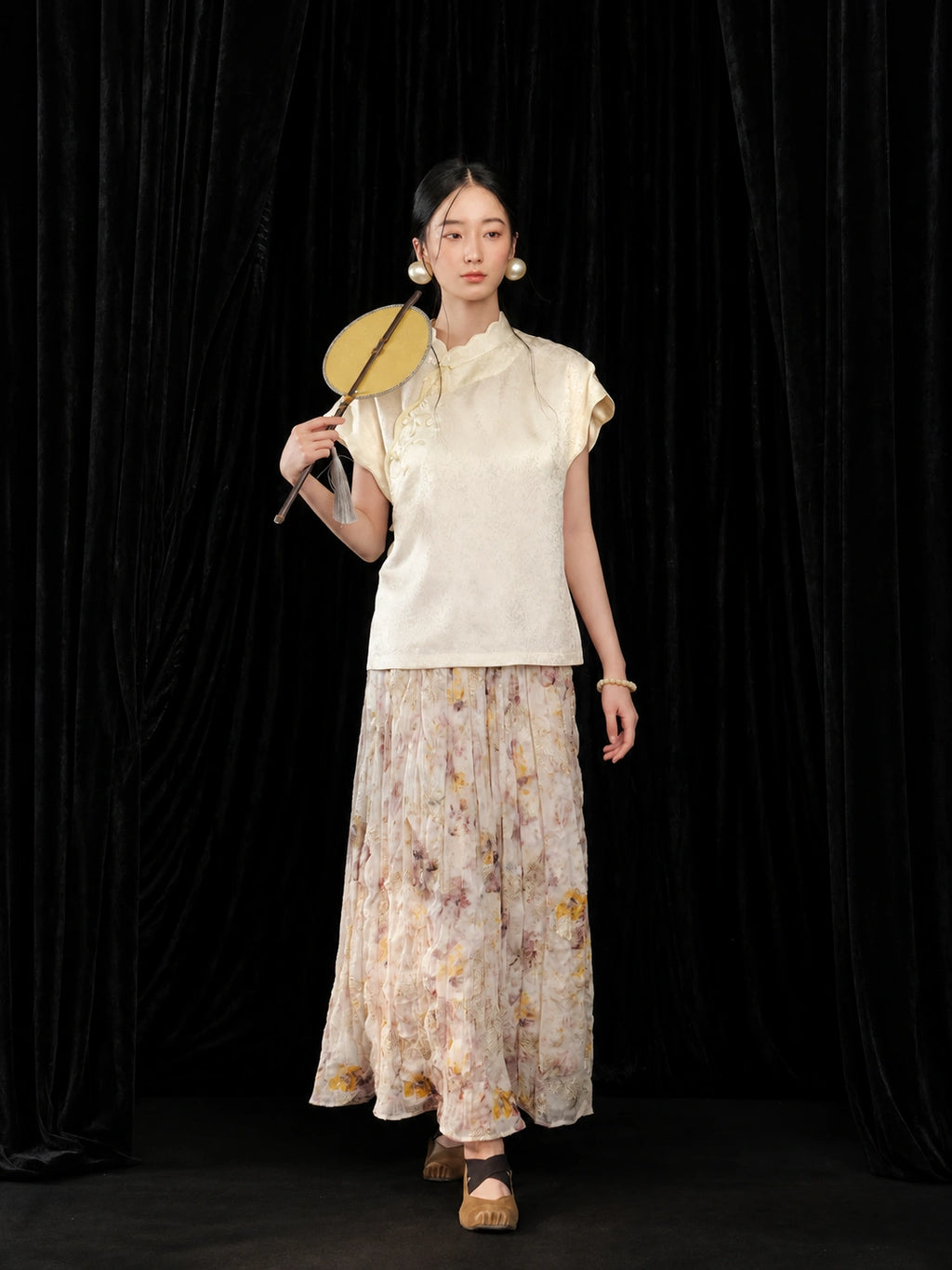 Full outfit view of the ivory silk qipao collar top styled with a floral skirt and handheld fan