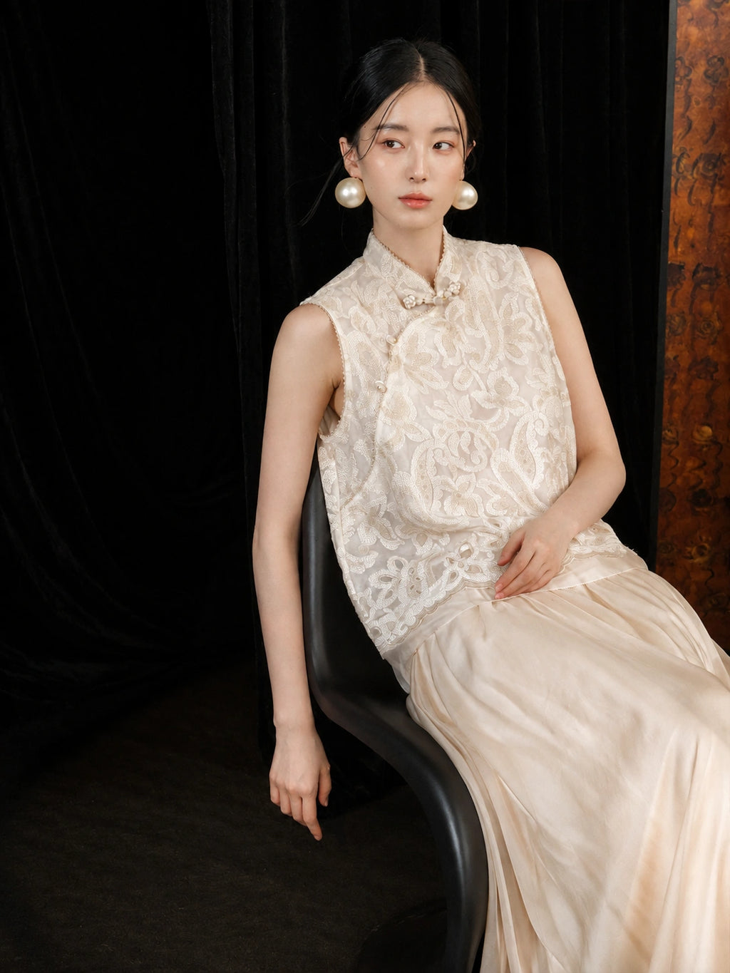 Elegant seated look featuring an ivory ankle-length silk skirt with a soft, graceful drape.