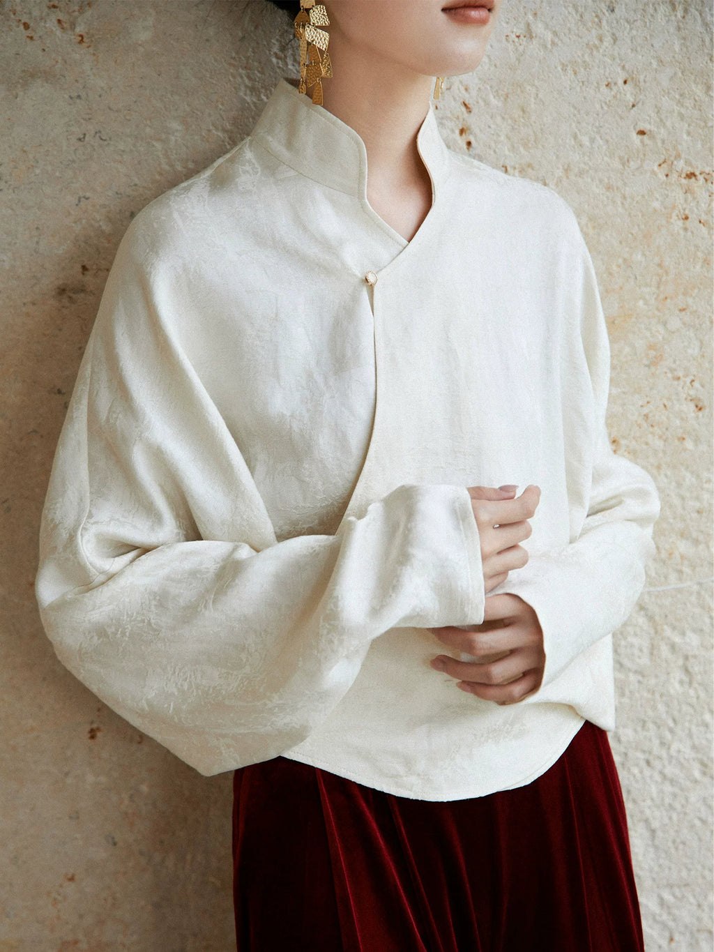Close-up of the ivory Mandarin collar wrap blouse showing the crossover neckline and fabric texture.