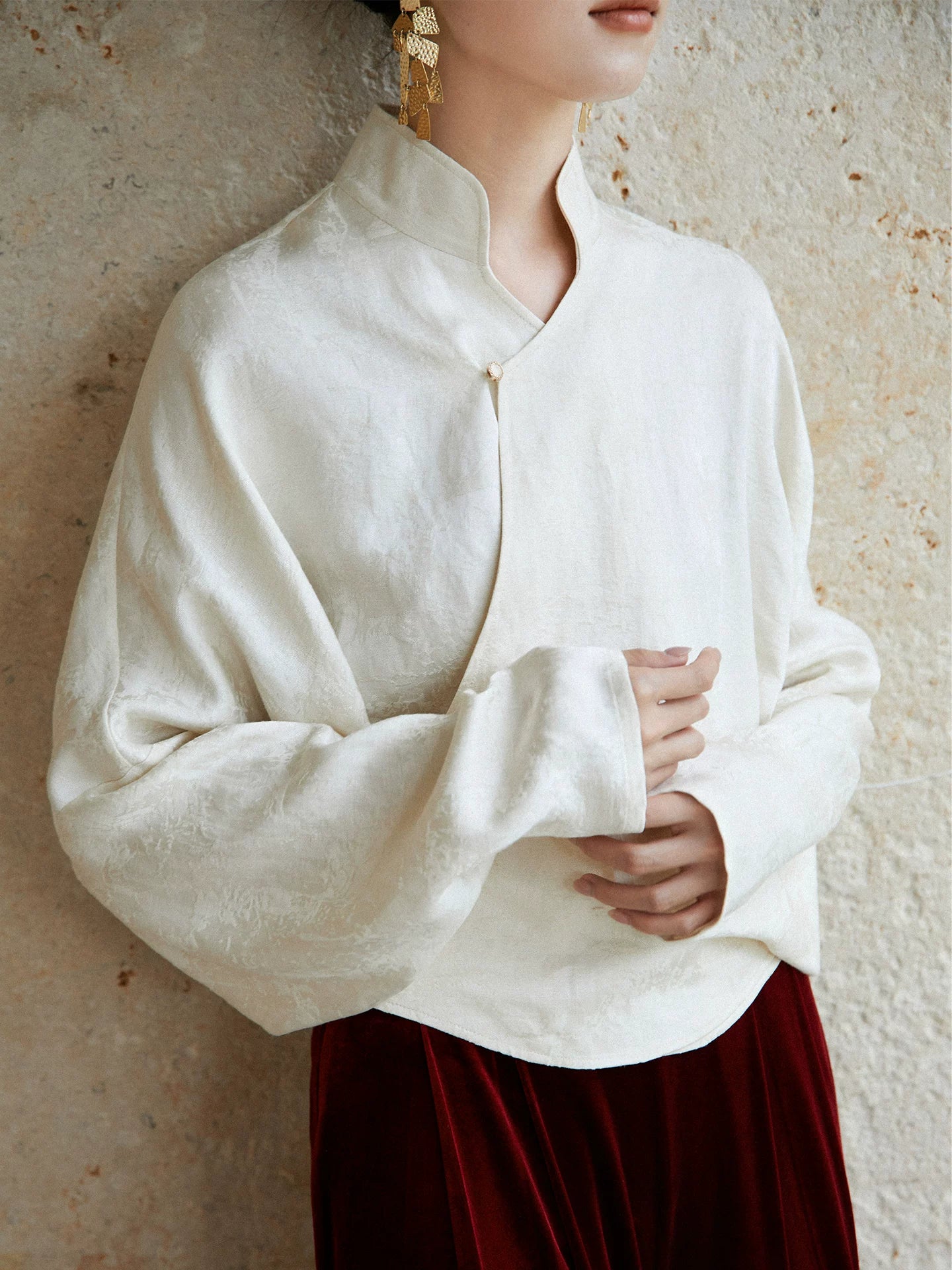 Close-up of the ivory Mandarin collar wrap blouse showing the crossover neckline and fabric texture.