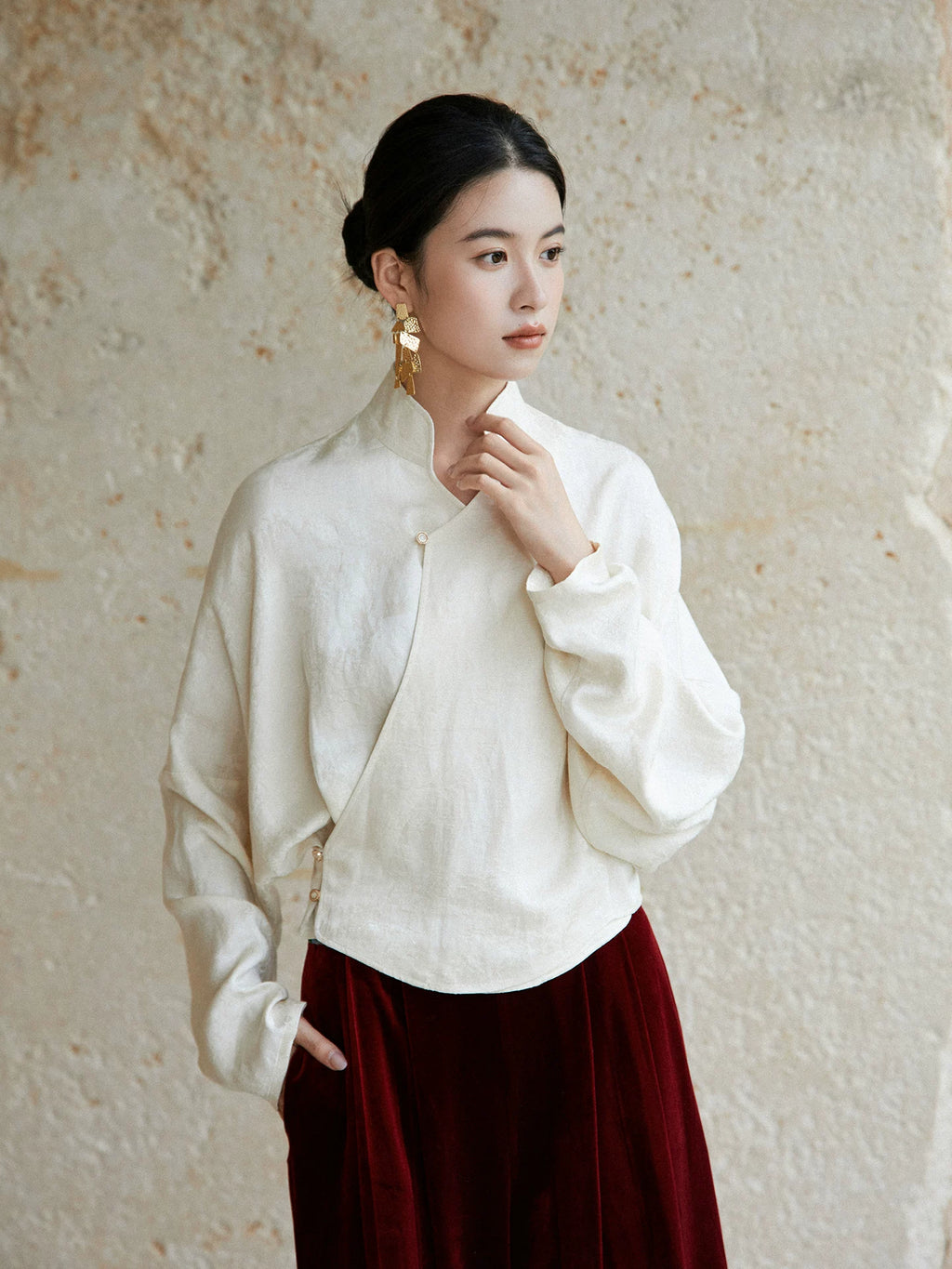 Side view of an ivory wrap blouse featuring a Mandarin collar and relaxed fit.