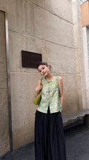 Full body shot of a vintage-inspired sleeveless Qipao top in watercolor jade green, crafted from 70% Lyocell and 30% Nylon, paired with black maxi pleated pants.